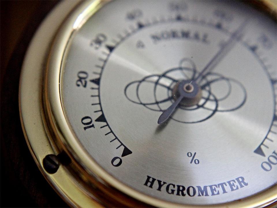 An analog hygrometer with a golden color