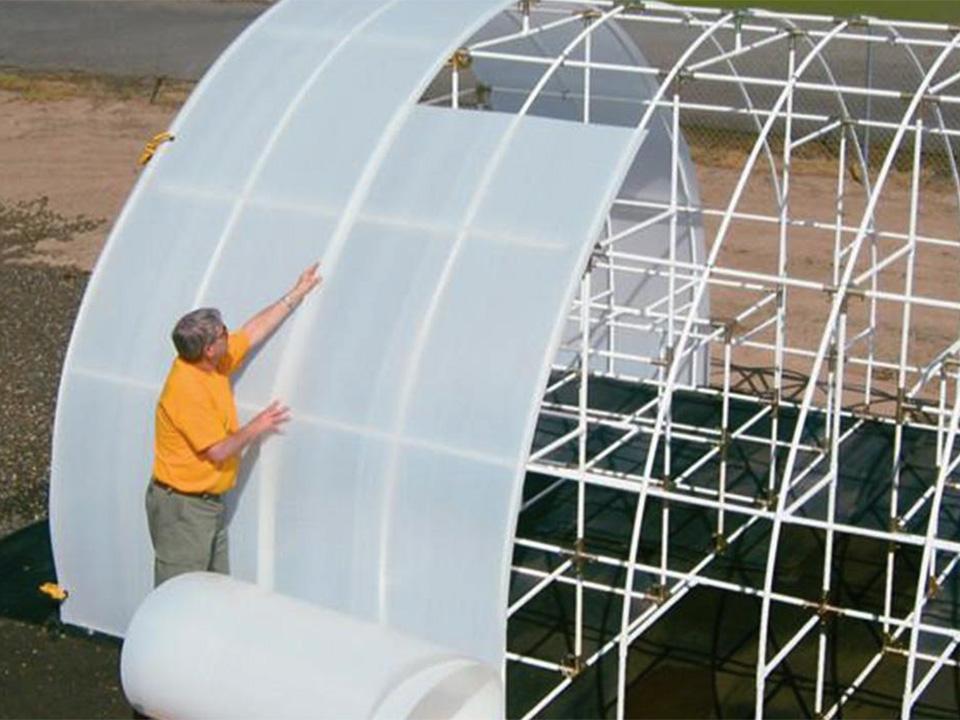 A man installing Solexx Greenhouse Covering Rolls 