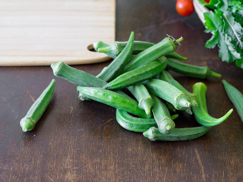 Several pieces of ready to cook Okra with a chopping board on the top left side