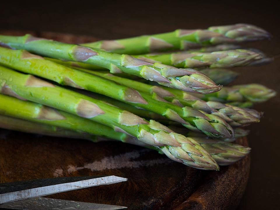 A bunch of asparagus with a scissor below
